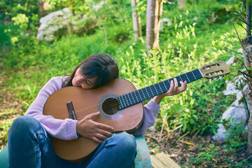 Hispanic woman holding a guitar and smiling while sitting on vintage chair on her porch