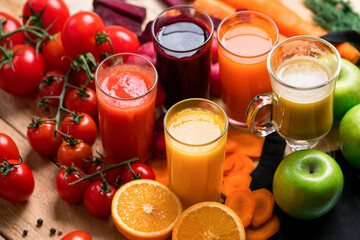 Close-up of a glass with yellow juice. Freshly squeezed juices in glasses of farm vegetables and fruits on wooden rustic table. Vitamin summer diet.