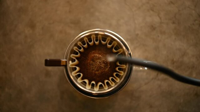 The barista is brewing coffee with traditional drip brewing equipment.