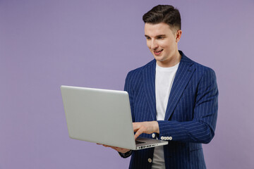 Young successful employee business man corporate lawyer 20s wear formal blue suit white t-shirt work in office hold use work on laptop pc computer isolated on pastel purple background studio portrait
