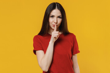 Secret beautiful young brunette woman 20s wears basic red t-shirt say hush be quiet with finger on...