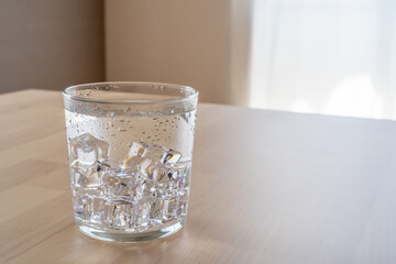 木製のダイニングテーブルの上に置かれた氷水の入ったコップ