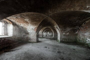 Fototapeta na wymiar Abandoned ancient catacombs, artillery warehouses, barracks of the coastal (naval) defensive fort of the 18th and 19th centuries, beautiful vaulted (arched) ceilings, side dense light from window.