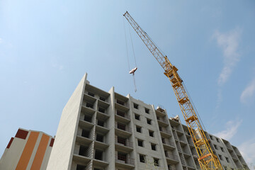 Fototapeta premium Unfinished building and construction crane outdoors, low angle view