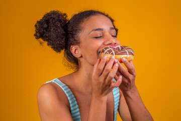 Young afro woman eating delicious chocolate donuts.