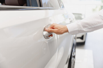 Close up man male hand customer buyer client in white shirt chooses auto wants to buy new automobile open car door handle in showroom vehicle salon dealership store motor show indoor Sales concept