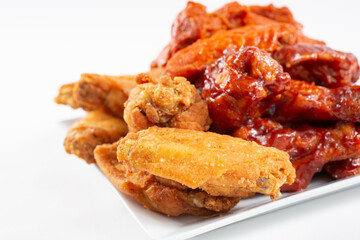 A view of a plate of a chicken wings sampler, featuring flavors as buffalo and BBQ sauce.