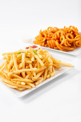 A view of a plate of french fries and a plate of curly fries.