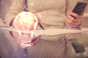 Double exposure of light bulb hologram and woman holding and using a mobile device. Idea concept.