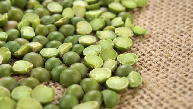 Organic dry split green peas on a rough rustic sackcloth. Macro. Dolly shot.