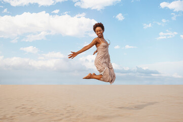 Young latin woman jumping for happiness in the desert or beach. Concept of freedom and happiness