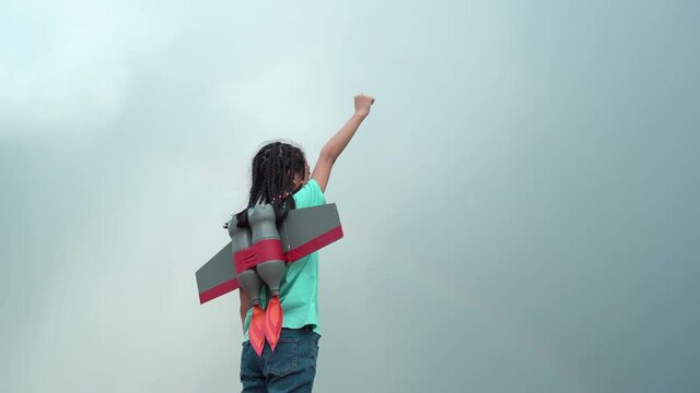 Side view of child girl playing outdoors with a toy rocket, Kid flying to the sky with a rocket jetpack like a superhero pilot.