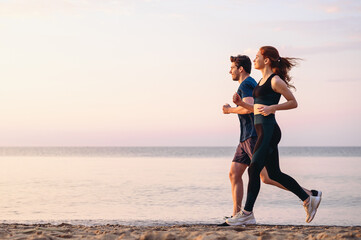 Full body profile couple young two friends strong sporty sportswoman sportsman woman man 20s in sport clothes warm up training run on sand sea ocean beach outdoor jog on seaside in summer day morning. - obrazy, fototapety, plakaty