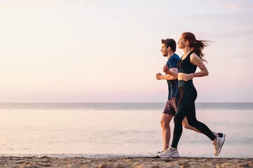 Foto op Aluminium Full body profile couple young two friends strong sporty sportswoman sportsman woman man 20s in sport clothes warm up training run on sand sea ocean beach outdoor jog on seaside in summer day morning. © ViDi Studio