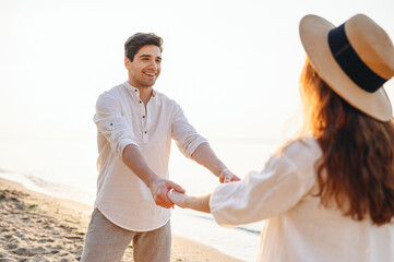 Young lovers fun couple two friends family man woman in white shirt clothes whirling by hands walk stroll dance together at sunrise over sea beach ocean outdoor exotic seaside in summer day evening.
