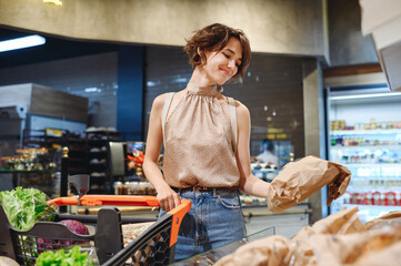 Young satisfied smiling woman wear casual clothes shopping at supermaket store with grocery cart...