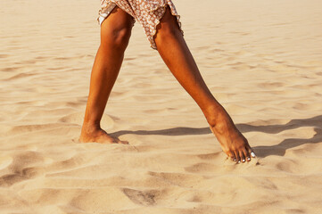 Latin woman feet in the sand at the time of the golden hour. Concept of freedom and contact with the earth