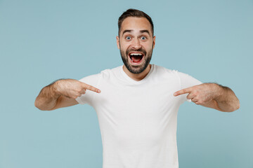 Young surprised amazed happy man 20s wear blank print design white t-shirt point index finger on...