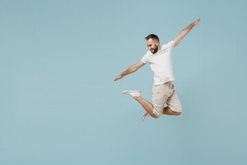 Obraz premium Full length young overjoyed fun cool happy excited caucasian man 20s wear casual white t-shirt jump high with outstretched hands isolated on plain pastel light blue color background studio portrait