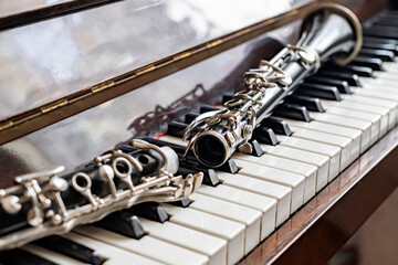 The clarinet, disassembled in half, lies on the piano by the sunny window.