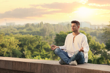 Fototapeta premium Man meditating outdoors on summer day. Space for text