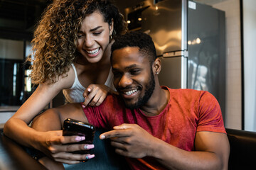 Young couple using a mobile phone at home.