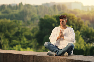 Fototapeta premium Man meditating outdoors on summer day. Space for text