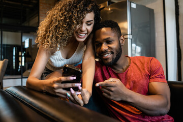 Young couple using a mobile phone at home.