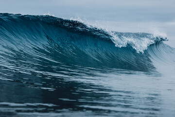 Perfect barrel wave on beach. Breaking ocean wave with cloudy weather