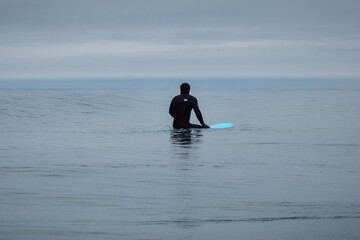Surfer in wetsuit sit on surfboard and waiting wave