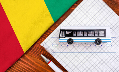 Toy bus and flag of Guinea. Travel concept