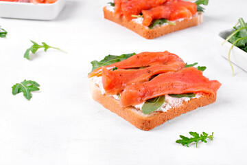 Toast with salted trout, cream cheese and arugula on the white table