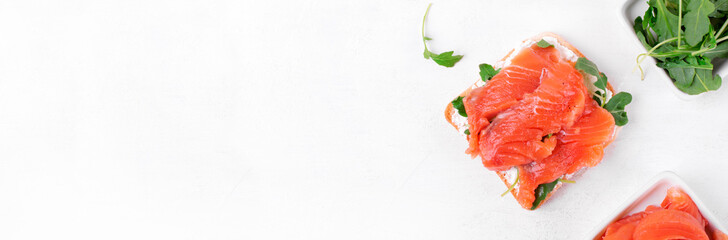 Toast with salted trout, curd cheese and arugula on the white table. Web banner with copy space