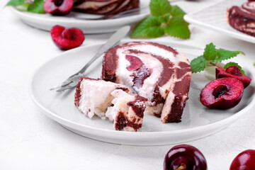 Biscuit roulade piece with cherry and cream served on the plate