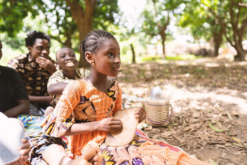 Attentive little African schoolgirl eagerly copying numbers on her chalkboars during open air...