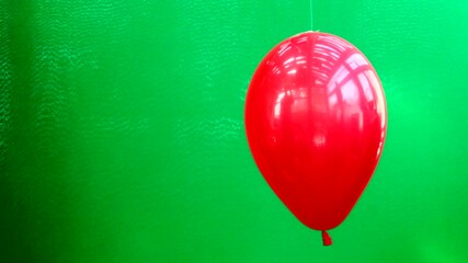 A red balloon on a green background bursts and smoke comes out of it
