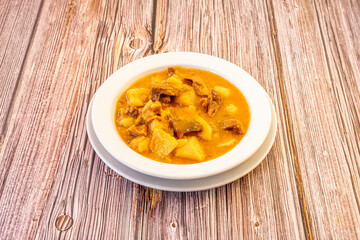 Great Castilian potato stew with meat and sauce for dipping bread on wooden table