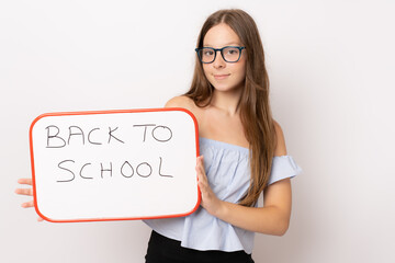Naklejka premium Young girl wearing glasses holding white board over white background. Back to school concept.