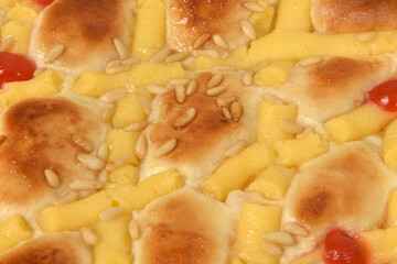 close up of sponge cake of egg cream, pine nuts and cherries on white background