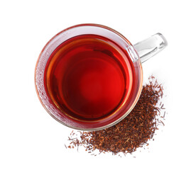Aromatic rooibos tea in glass cup and scattered dry leaves on white background, top view