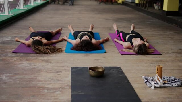 The shavasana. Women laying on mat in relaxing pose on the floor, front view, yoga class