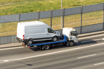 Loading minibus on a tow truck on city street.