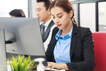 Portrait of young Asian business woman sitting by PC computer laptop on the table in the office. Beautiful girl looking at the camera. Startup business Asia woman with online marketing