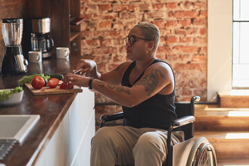 Side view portrait of contemporary tattooed woman with disability cooking dinner at home, copy space