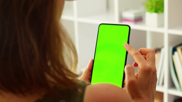 A woman is using a mobile phone with a green screen. Empty space on a smartphone.