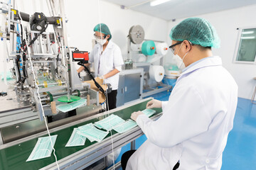 male factory worker are producing medical face masks and checking of quality from machine