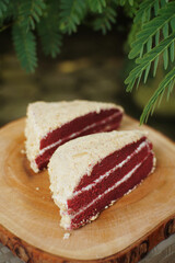 Close up of red velvet cake with green plants in the background.