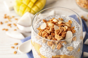 Delicious chia pudding with granola and mango in glass on table, closeup