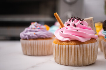 Delicious homemade cupcakes with Colorful cream and topping with candy and Chocolate Cookies. Homemade autumn holiday dessert