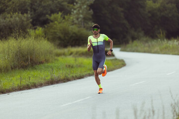 Young professional male triathlete, runner in motion on open road. Concept of sport, lifestyle,...